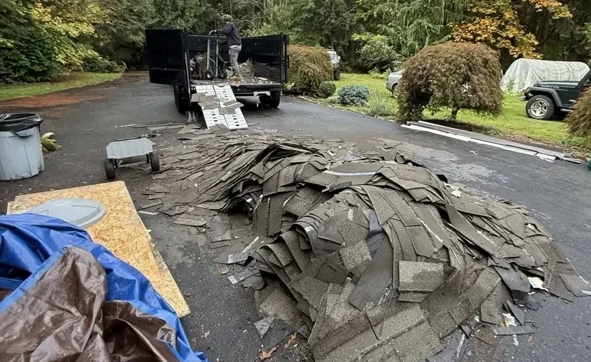 Dump trailer with loading ramp being filled with old roof shingles during a roofing debris removal job in Snohomish County