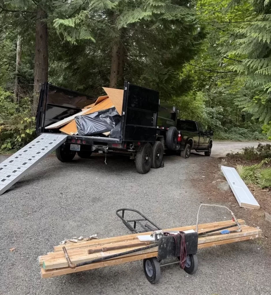 Dump trailer loaded with wood, cabinet pieces and bagged renovation debris